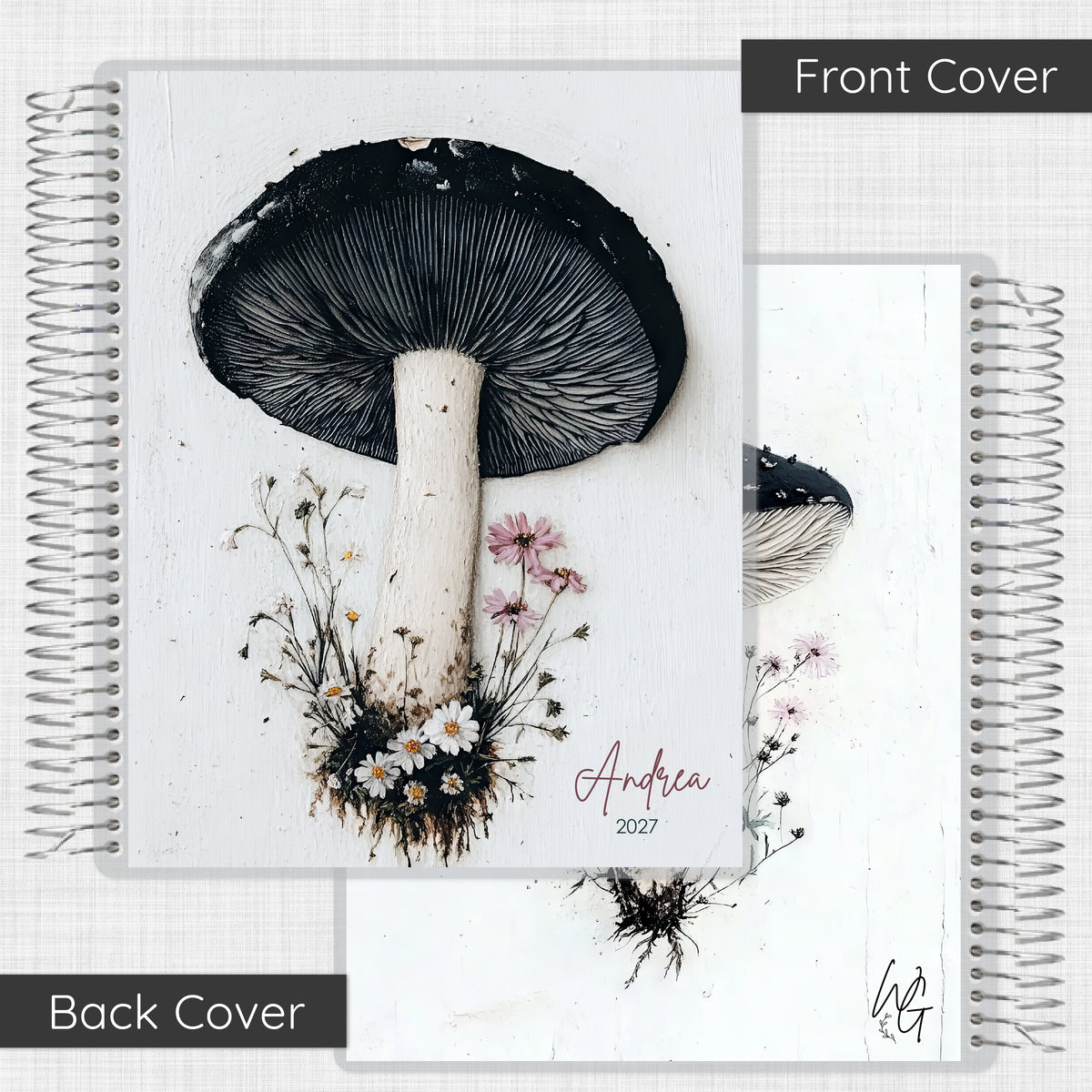 A spiral-bound notebook shown from both front and back covers. The front cover features a large black-and-white mushroom illustration with small pink and white flowers, and the name 'Andrea 2027' in script.