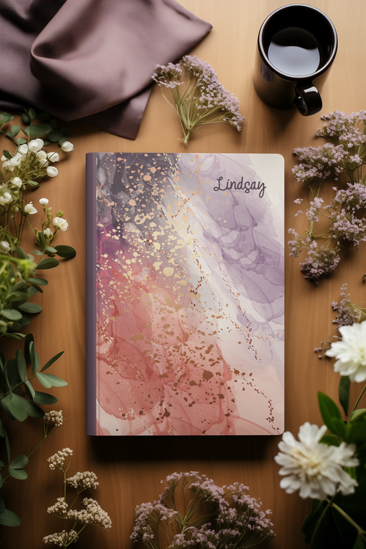 a notebook with a colorful, abstract design, surrounded by various floral elements and a cup of coffee on a wooden surface.